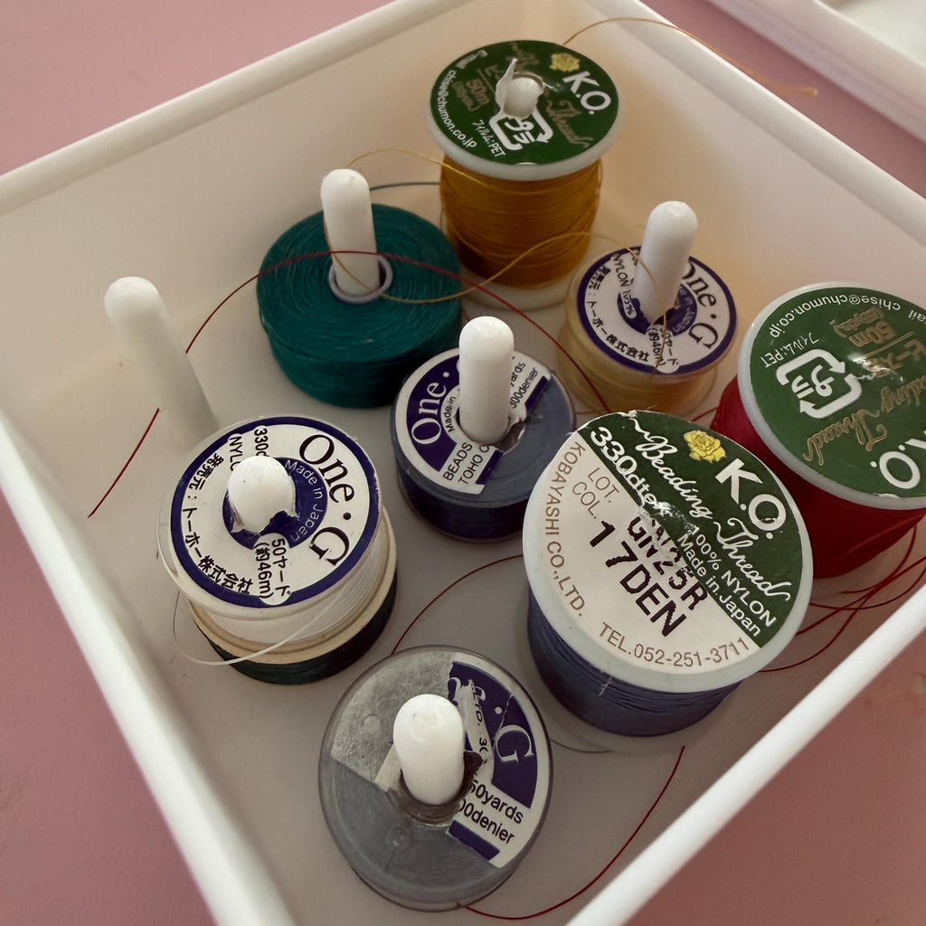 Collection of spools of thread with visible brand labels on a pink background